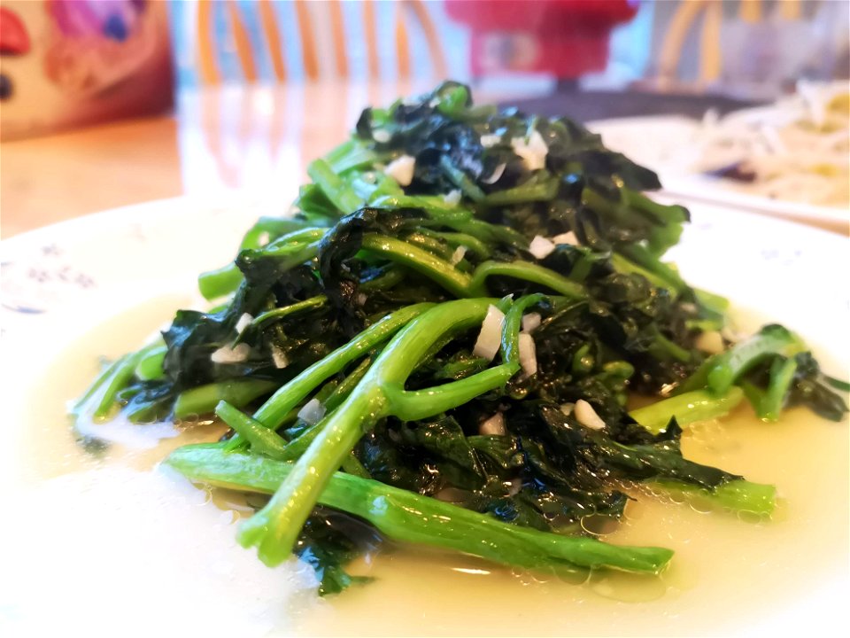 A dish of stir-fried watercress with garlic. Another dish (stir-fried bean sprouts) is visible in the background.