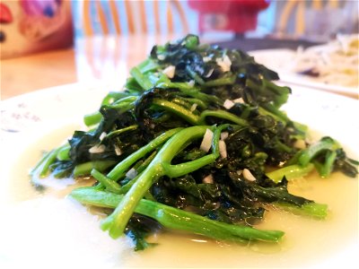 A dish of stir-fried watercress with garlic. Another dish (stir-fried bean sprouts) is visible in the background.