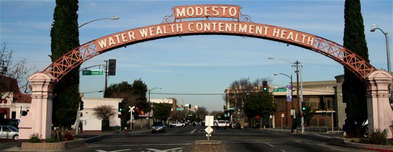 The Modesto Arch, first erected in 1912, by a level crossing in Modesto, north central California. The slogan is the city's motto: "Water, wealth, contentment, health".