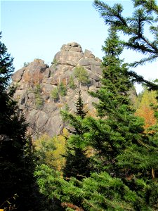 Rock "1 Stolb" in Stolby Nature Reserve, Krasnoyarsk, Russia. Abies sibirica trees in foreground
