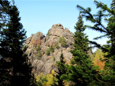 Rock "1 Stolb" in Stolby Nature Reserve, Krasnoyarsk, Russia. Abies sibirica trees and foliage in foreground.