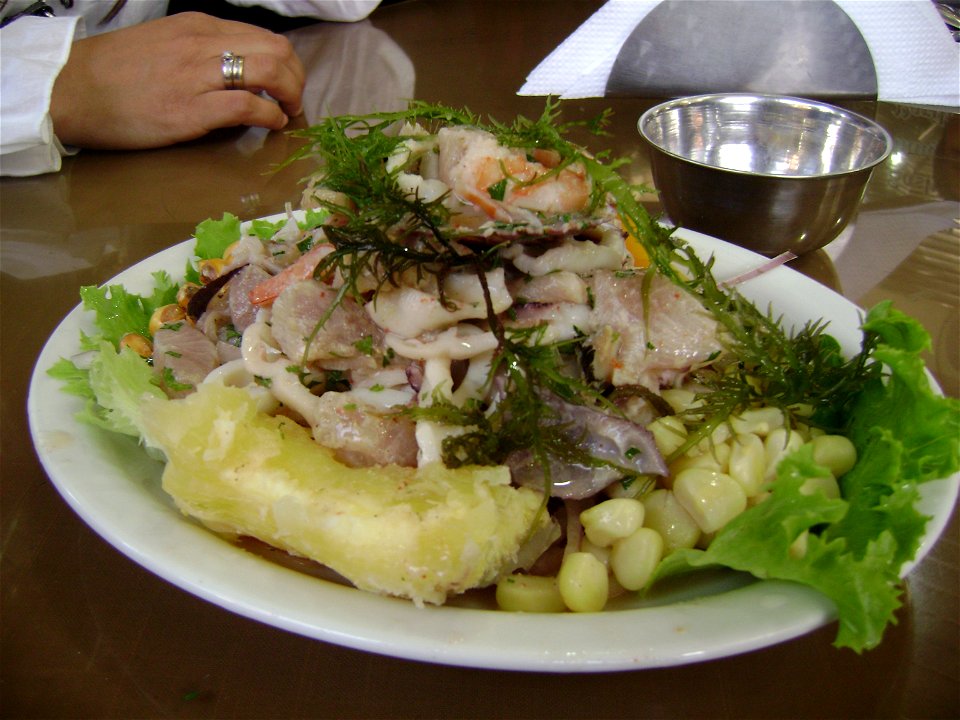 Un plato de Ceviche Mixto (pescado, mariscos)servido con granos de choclo, porciones de yuca y yuyo (alga marina)