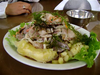 Un plato de Ceviche Mixto (pescado, mariscos)servido con granos de choclo, porciones de yuca y yuyo (alga marina)