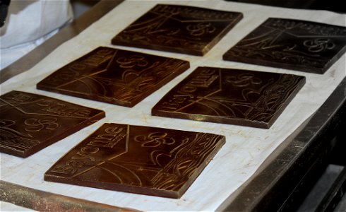 Confection des carrés en chocolat noir à l’effigie de la ville de Bayonne. Fabrication à l'Atelier du Chocolat, Bayonne, Pays Basque.