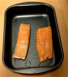 A pedagogical image related to the "Procedure (detailed)" "Method" steps in Wikibooks Cookbook:Salmon with Rice and Sauce (Q86594655) Step 21: Putting salmon in cake tin, preparing to later put it in photo