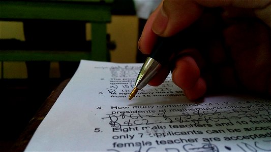 A student answering a test. The ballpoint pen and the hand of the student is shown.