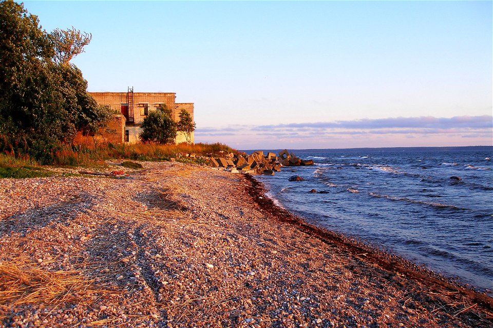 A shingle beach at the coast of Hara Bay in Suurpea, Lahemaa National Park, Estonia. Abandoned Soviet military building in the background.