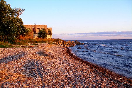 A shingle beach at the coast of Hara Bay in Suurpea, Lahemaa National Park, Estonia. Abandoned Soviet military building in the background.
