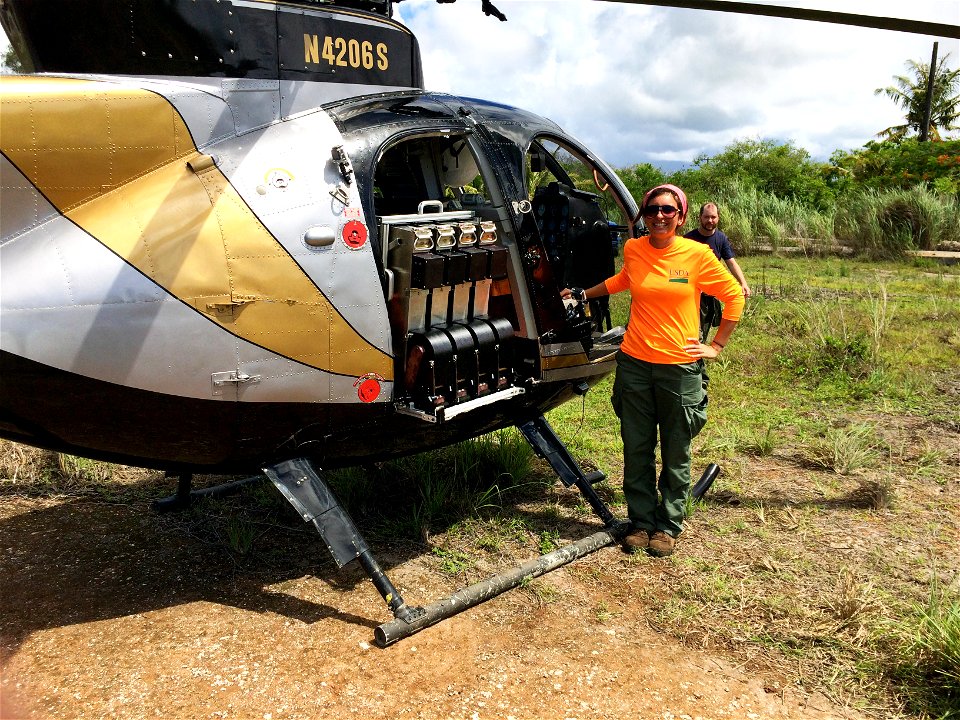 Wildlife Service employee Rachael Volsteadt looks over the automated aerial Brown Tree Snake bait delivery system attaches to a helicopter and allows for the dispersal of up to four bait cartridges pe