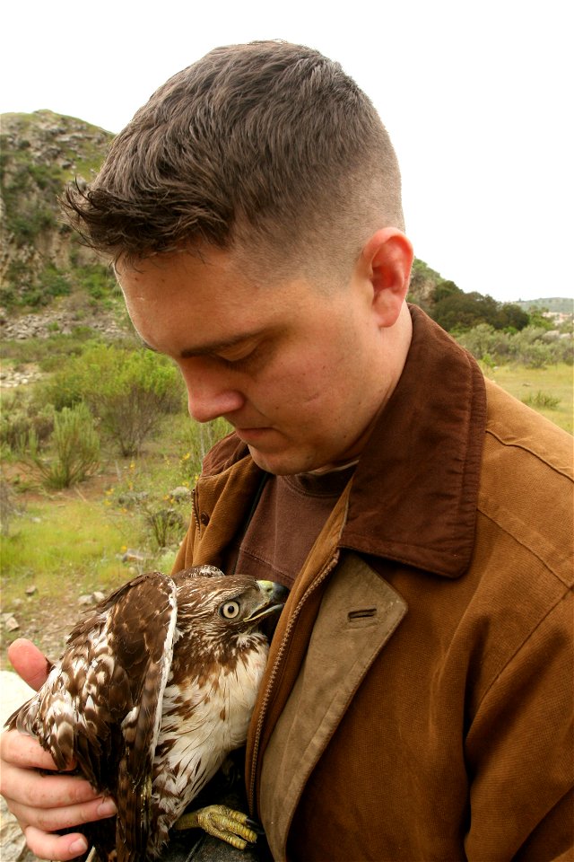 Sgt. Thomas Parker, a ground safety manager with Marine Light Attack Helicopter Training Squadron 303, Marine Aircraft Group 39, 3rd Marine Aircraft Wing, clutches his red tail hawk, Akando in an atte