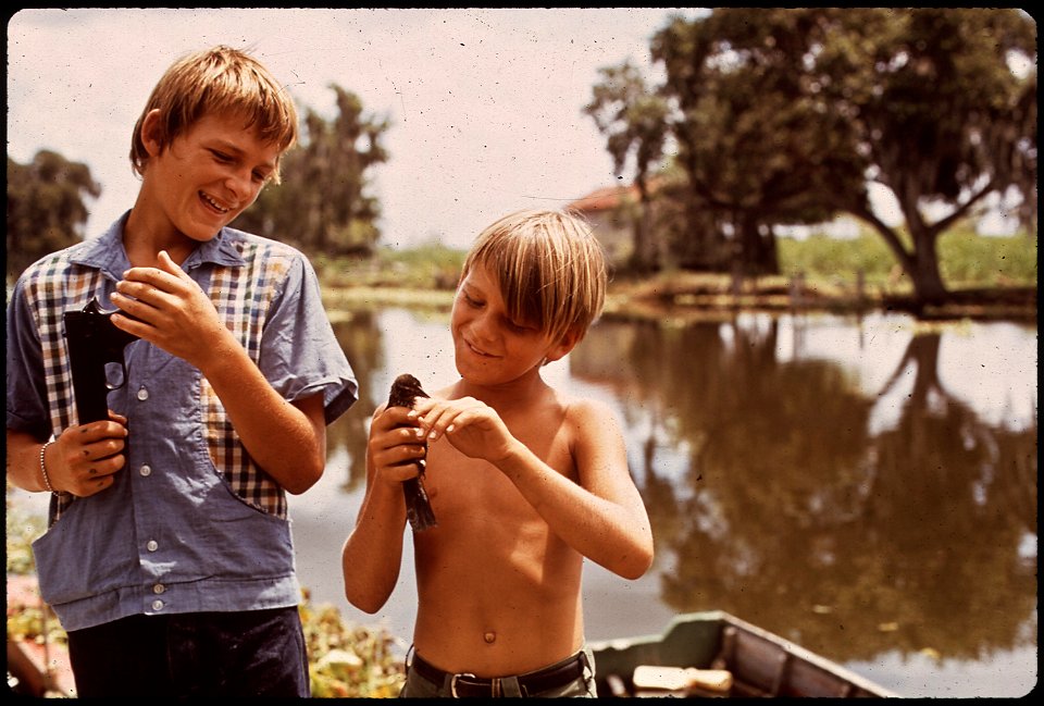 BOYS WITH AIRGUN AND BIRD. THESE FISHERMAN'S SONS LIVE IN BAYOU GAUCHE, DEEP IN THE WETLANDS OF LOUISIANA