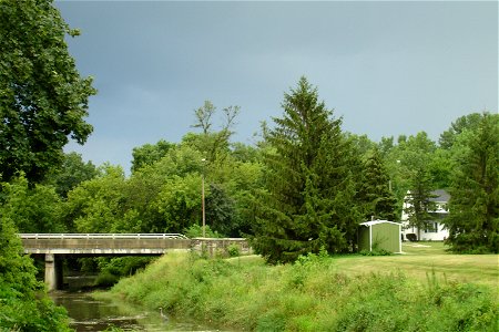 A mid-September thunderstorm rolls into DeKalb over the Kishwaukee River.  A great blue heron stands in the river near a bridge.