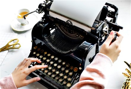 Aerial view of a woman typing on a retro typewriter blank paper