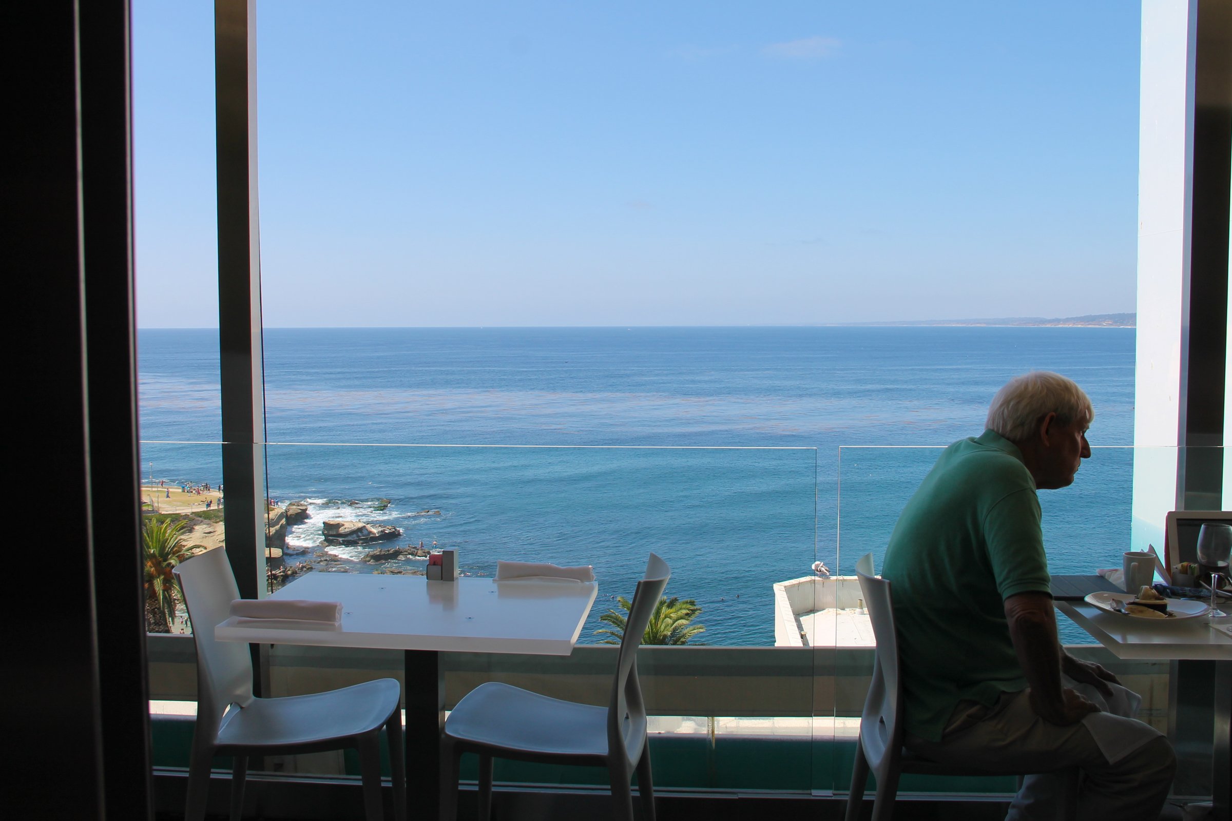 Elderly Man Sitting in Restaurant by Ocean photo