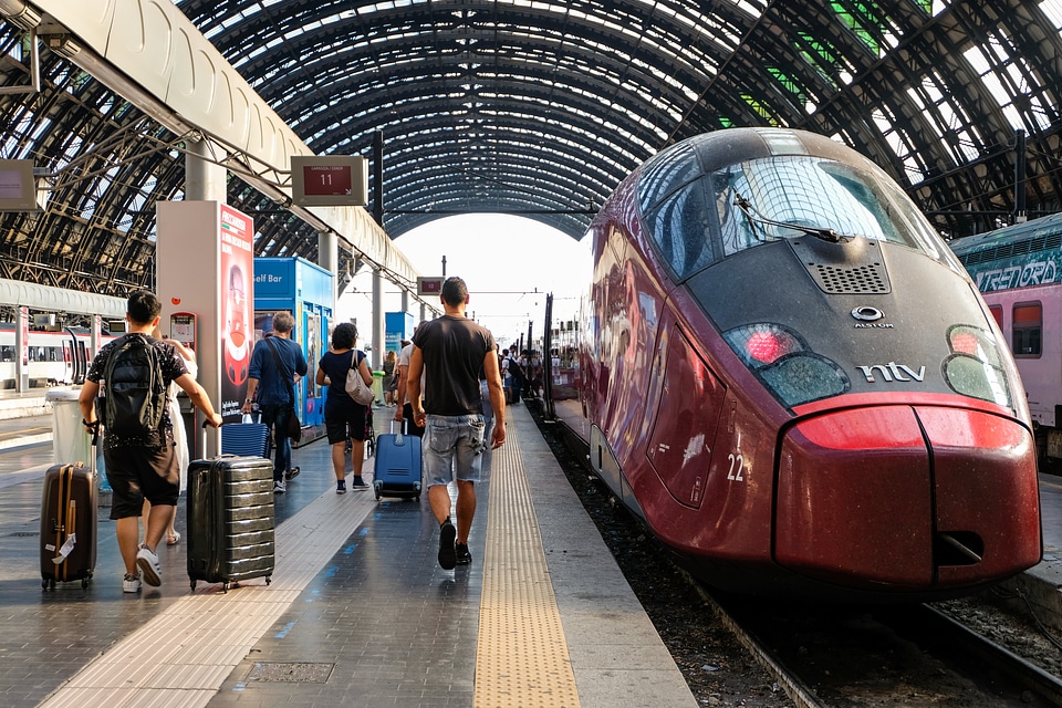 People Walking Towards the Train with Trollers in a Train Station photo