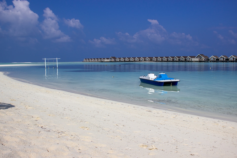 Pedalo Boat on Seashore with Houses on Water Behind It