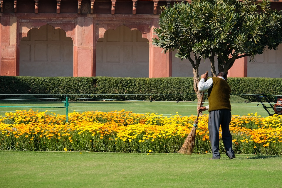 Gardner Sweeping the Leaves to Clean up the Garden