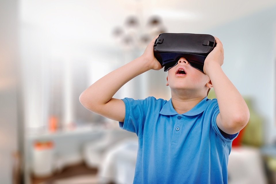1 Amazed teen boy wearing virtual reality goggles watching movies or playing video games.