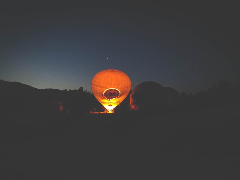 In the distance, another balloon gets filled up against the night sky. 