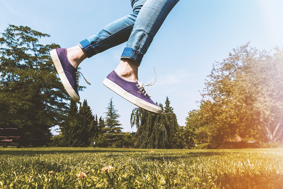 Female legs jumping on the grass outdoors in the park