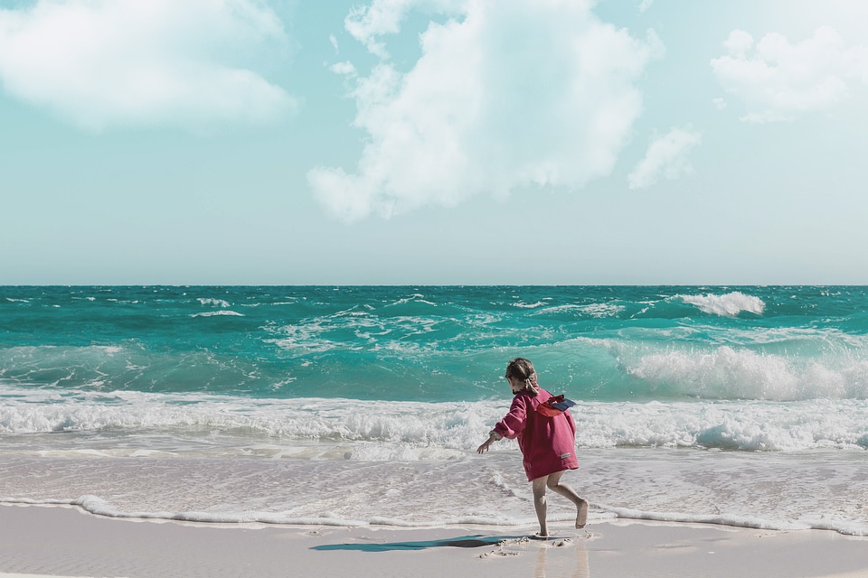 Happy little girl playing on beach