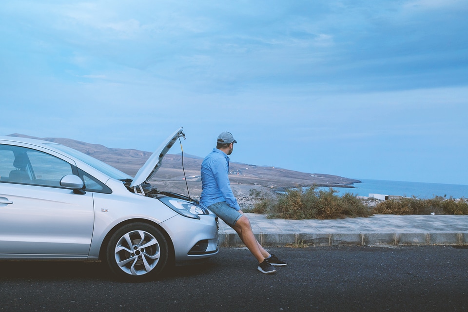 Angry man sitting on a broken car photo