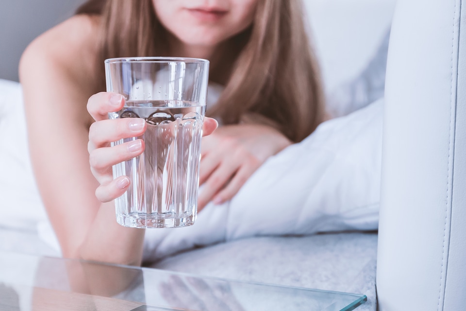 2 Close up Woman holding glass of water on bed in the morning