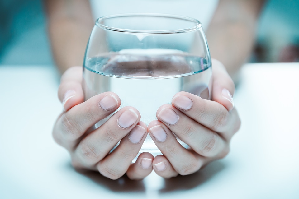 Female hand holding a glass of clean water, close-up.