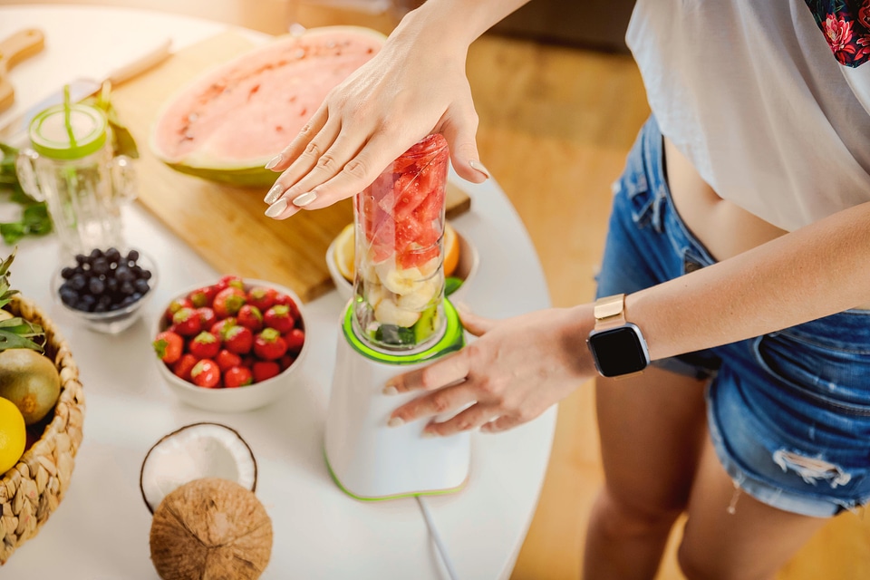 2 Hands of woman preparing smoothie fruit drink