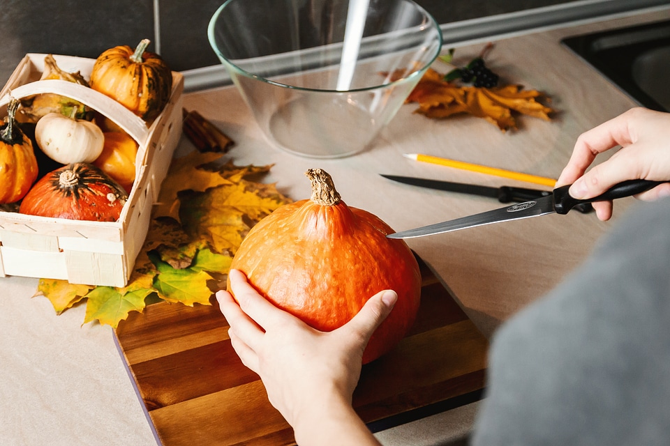 3 Girls hands carve the pumpkin. Halloween.