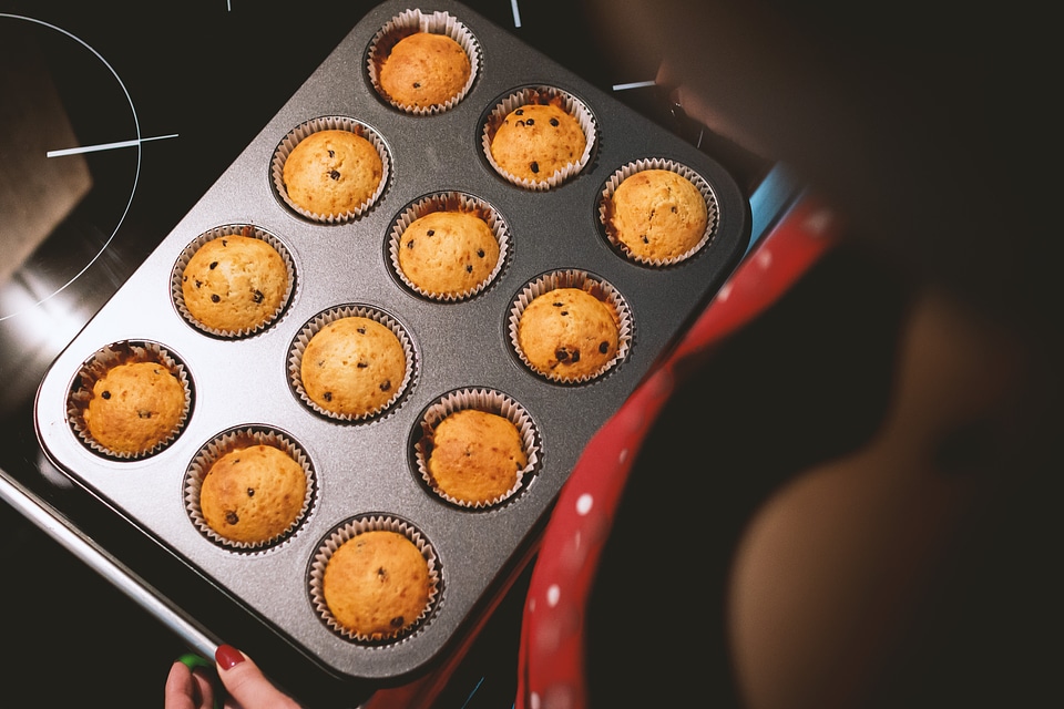 Baking pan with fresh muffins and young girl