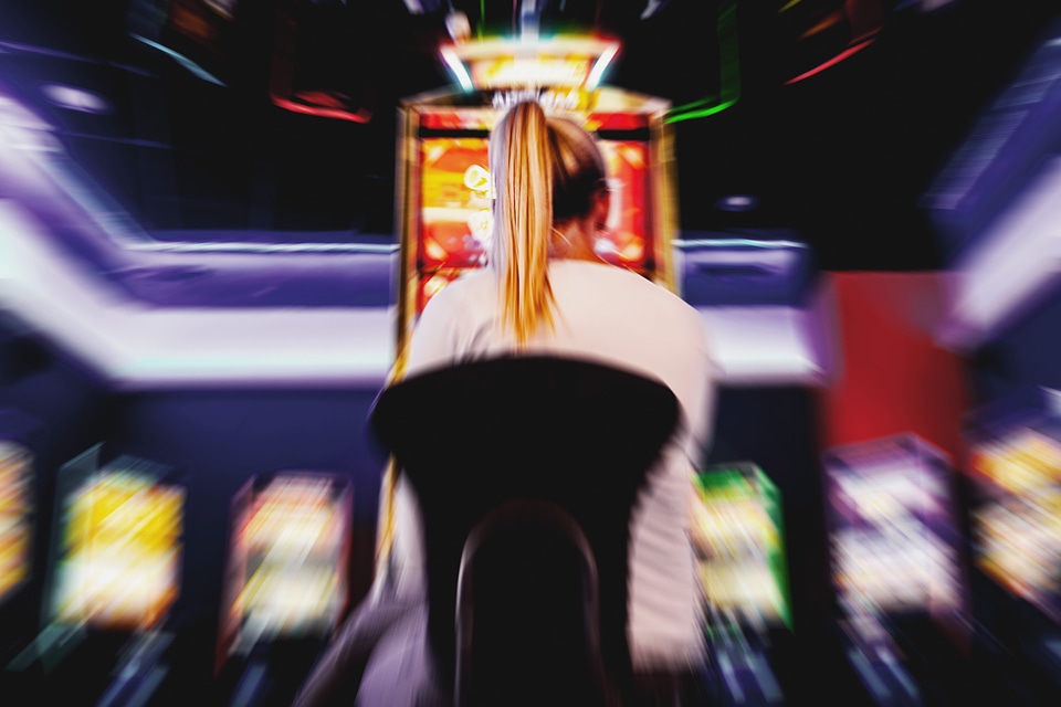 Blurred background of person in casino playing slot machine