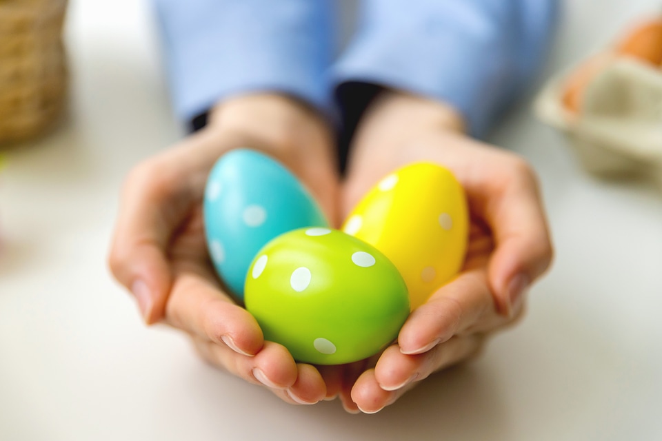 Woman’s hands holding modern painted easter eggs.