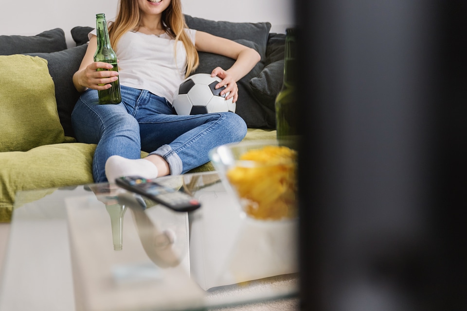 Very excited young woman watching football sport on tv at home.