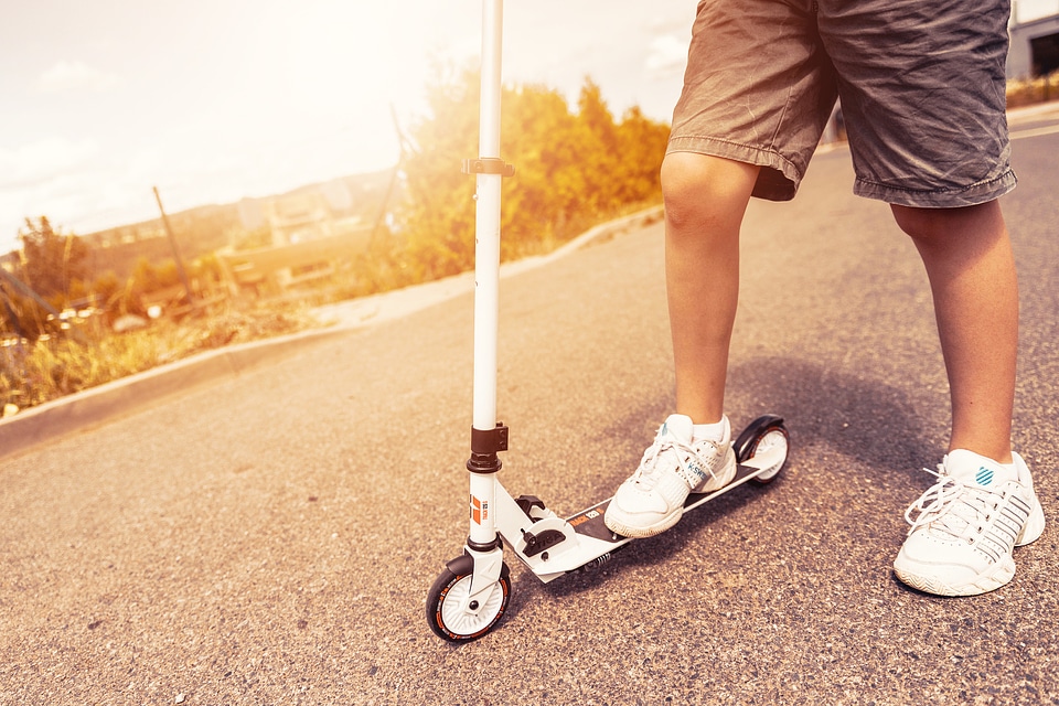 Child riding scooter outdoors. Active sport kids.