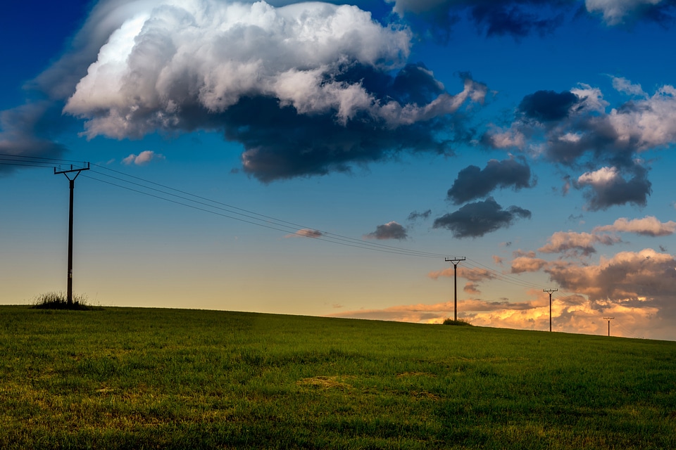 Amazing meadow with epic blue sky with big clouds at early evening