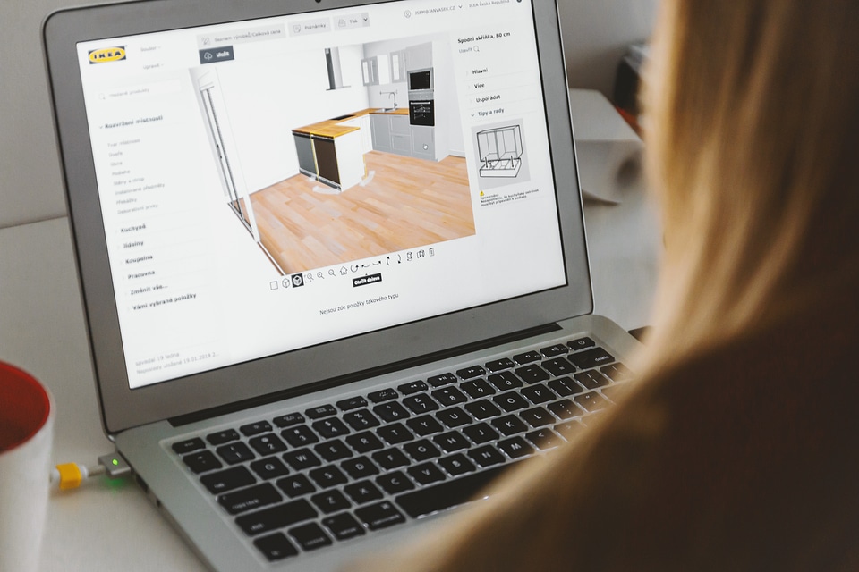 Woman uses 3D planning software for her new kitchen on laptop at home