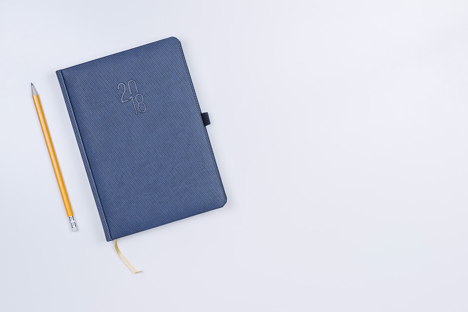 Pretty diary with a pencil on the white table.