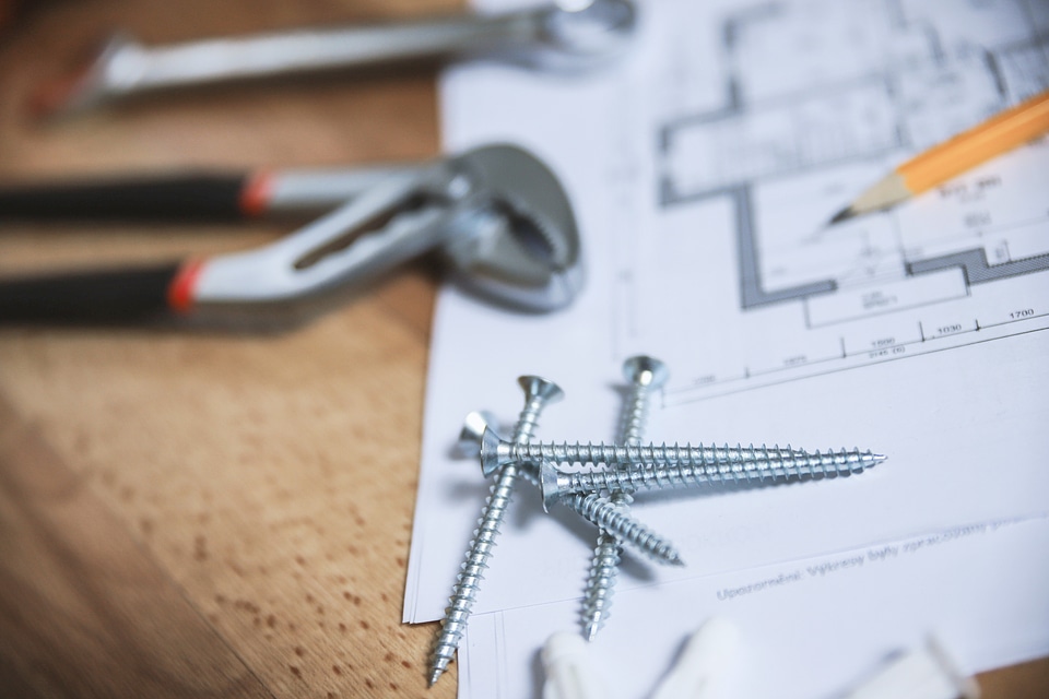 Close up screws and other tools with plans for the apartment