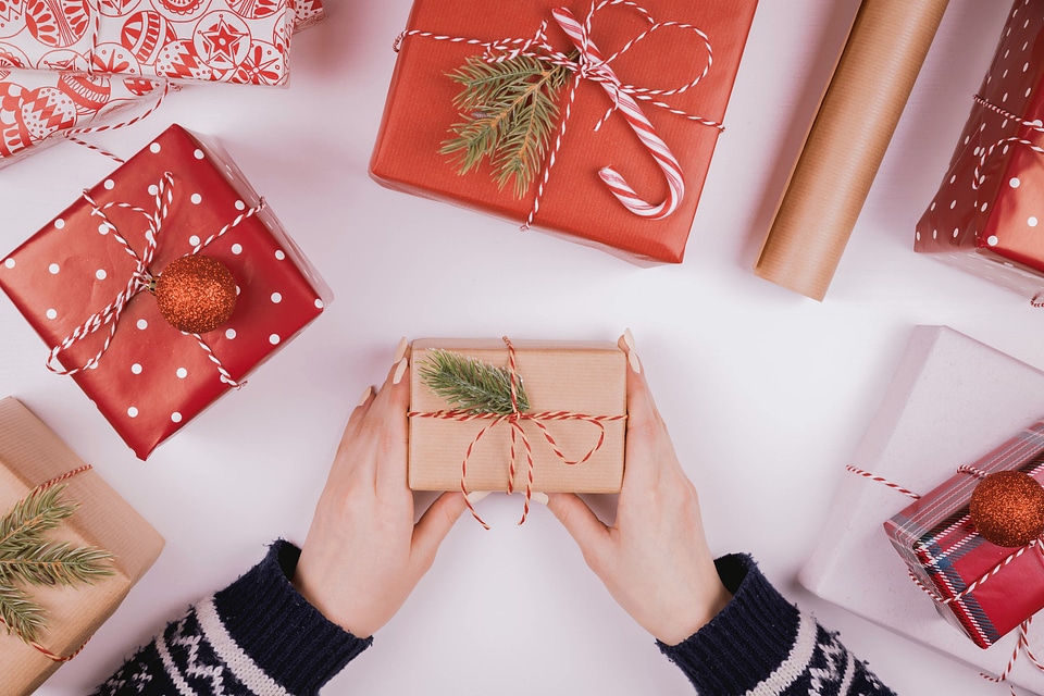 2 Woman holding Christmas presents laid on a white table background