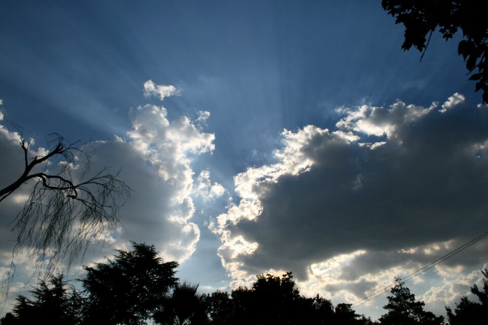 Light surrounding clouds light beams eminating blue sky