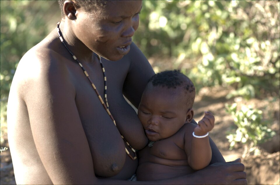 Hadzabe brat full at the in his mother's lap