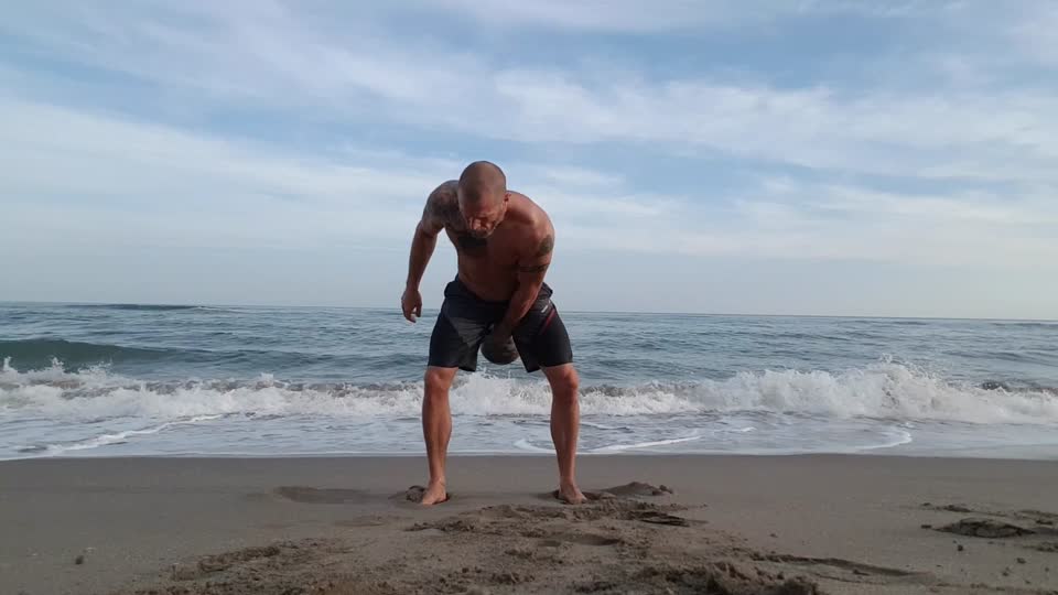 Kettlebell juggling beach no shirt