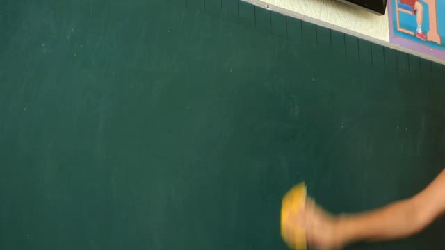 The teacher writes homework the teacher wipes the board yellow cloth