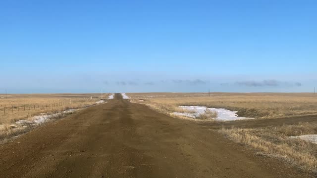 Gimbal shot driving W on County Road turning NW onto road on State Land