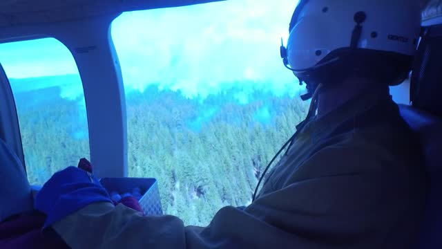 Crew Member Surveys Smokey Forest from a Helicopter