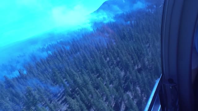 Crew Member Surveys Smokey Forest from a Helicopter