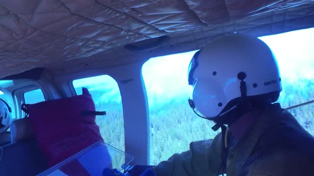 Crew Member Surveys Smokey Forest from a Helicopter