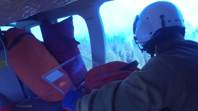 A Crew Member Surveys a Smokey Forest from a Helicopter
