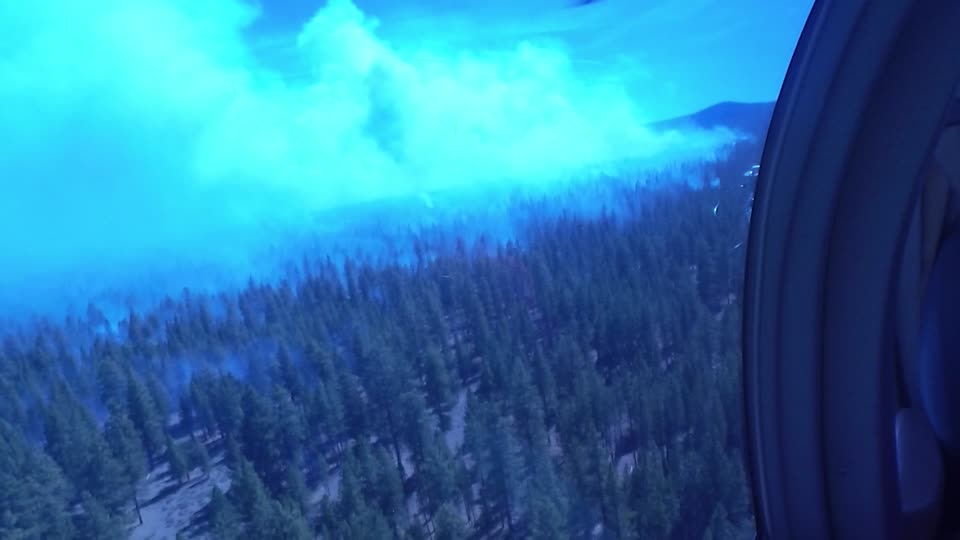 Crew Member Surveys Smokey Forest from a Helicopter